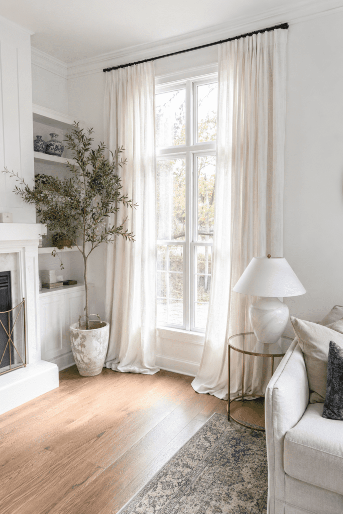 Bright living room styled to look expensive on a budget with cream sofa, layered pillows, marble tray, and warm lamp lighting.