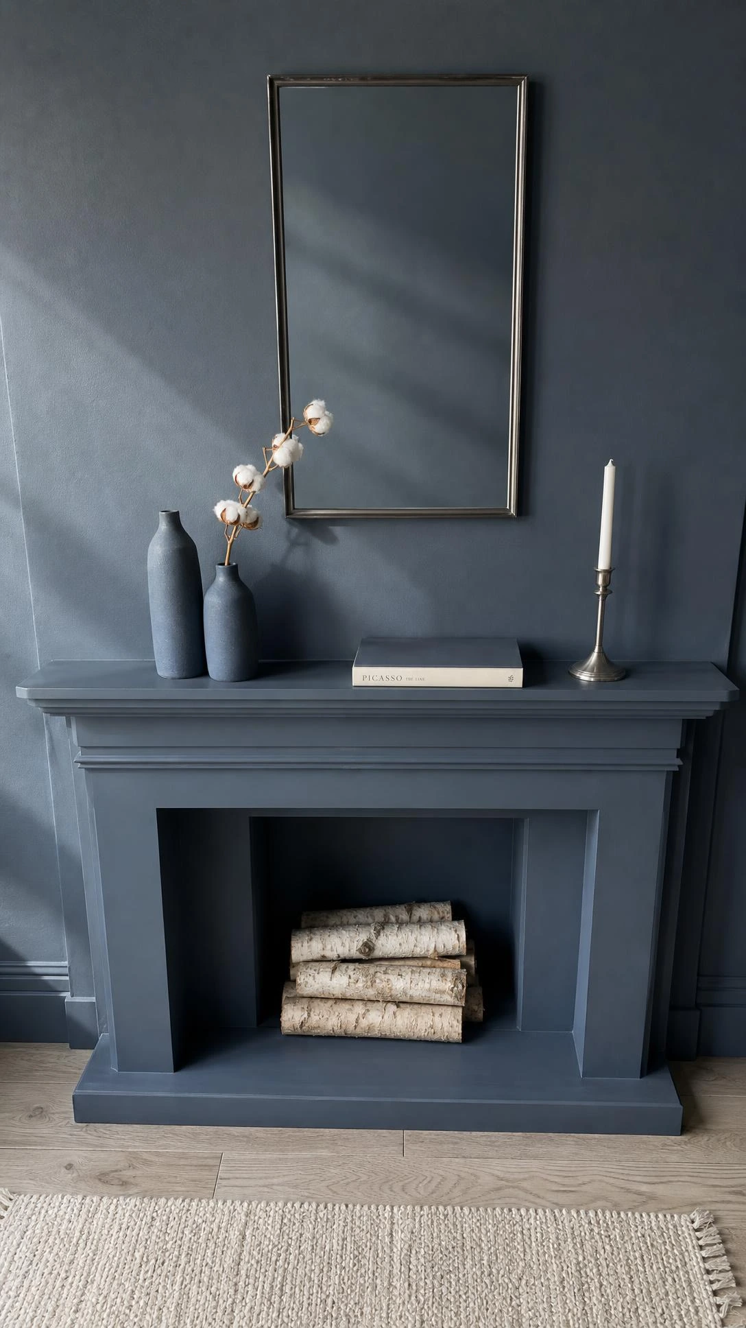 Overhead flat lay of a color-matched dusty slate blue fireplace wall where mantel, trim, and paint blend seamlessly, making a small living room feel intentionally designed