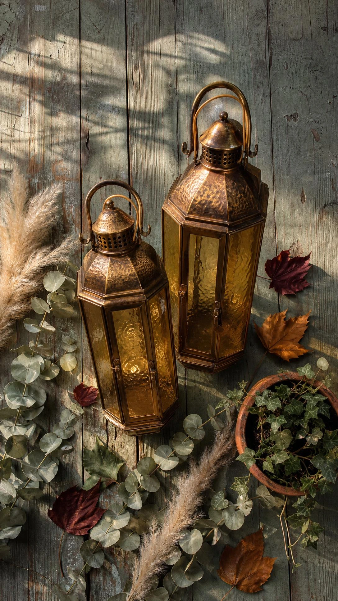 Two antique brass lanterns with amber glass panels on weathered wood, warm golden light reflected across the surface — a curb appeal upgrade through contrast and warmth