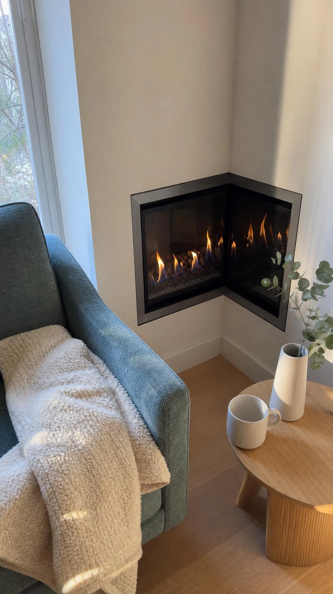 Corner gas fireplace with glowing amber flames fitted seamlessly into a small living room wall junction, showing how compact design maximizes tight spaces