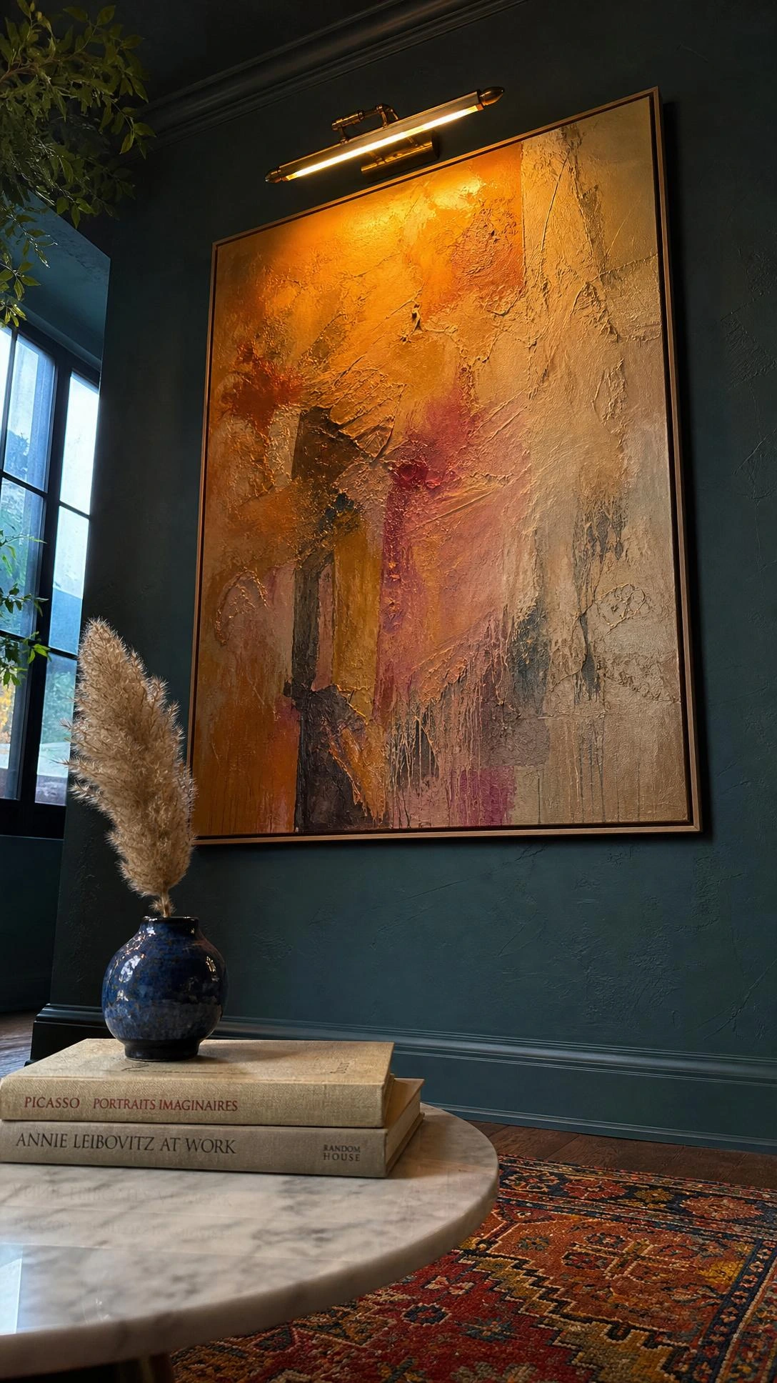Oversized abstract canvas lit by a single picture light on a moody teal-green plaster wall, showing how statement art anchors an eclectic luxury room