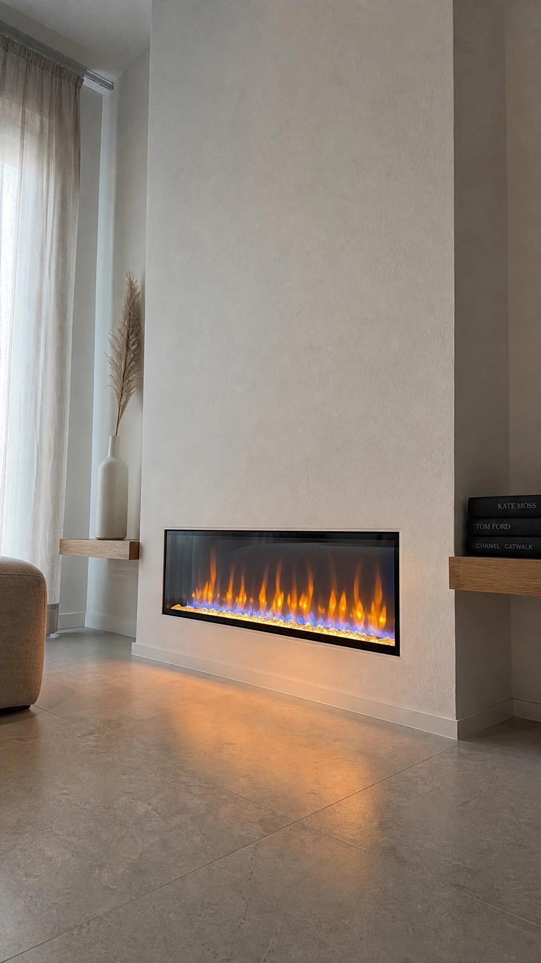 Glass front electric fireplace recessed flush into white drywall in a small living room, with glowing amber and blue simulated flames adding depth without consuming floor space