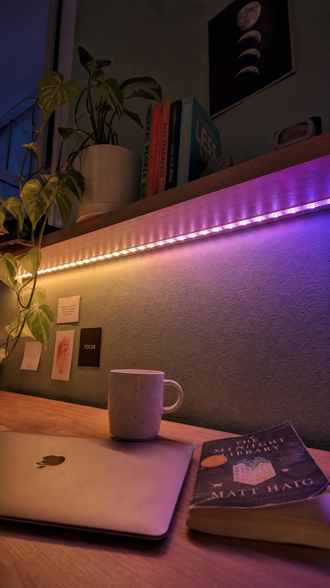 LED light strip glowing in violet and white gradient along underside of dorm room floating shelf, transforming a plain wall into a moody lit study corner at night