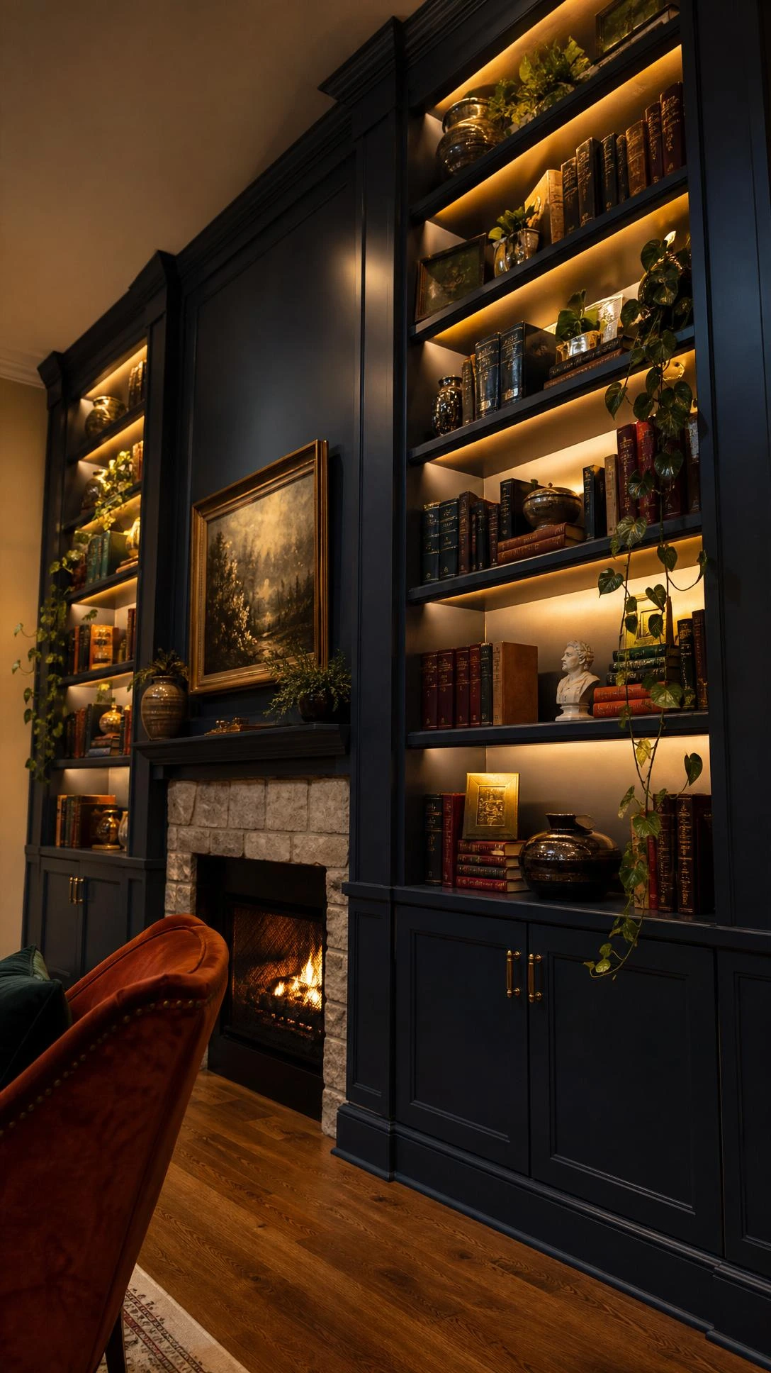 Floor-to-ceiling navy blue built-in bookcase with brass hardware flanking a stone fireplace, shot from a low angle to highlight dramatic vertical height and LED-lit shelving ambiance