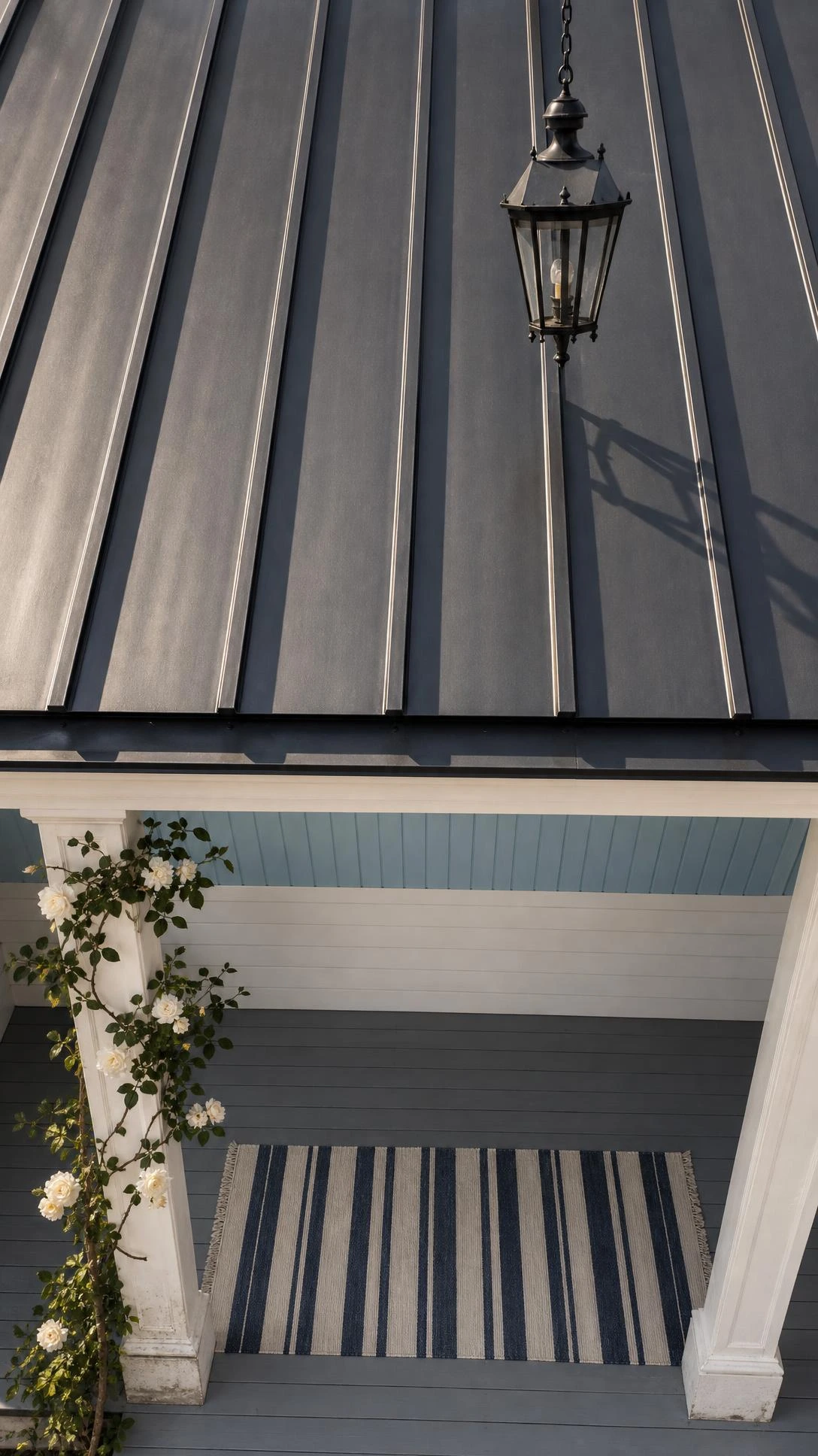 Standing seam metal roof in deep charcoal slate on a traditional covered porch, showing clean parallel ridges that modernize classic architecture