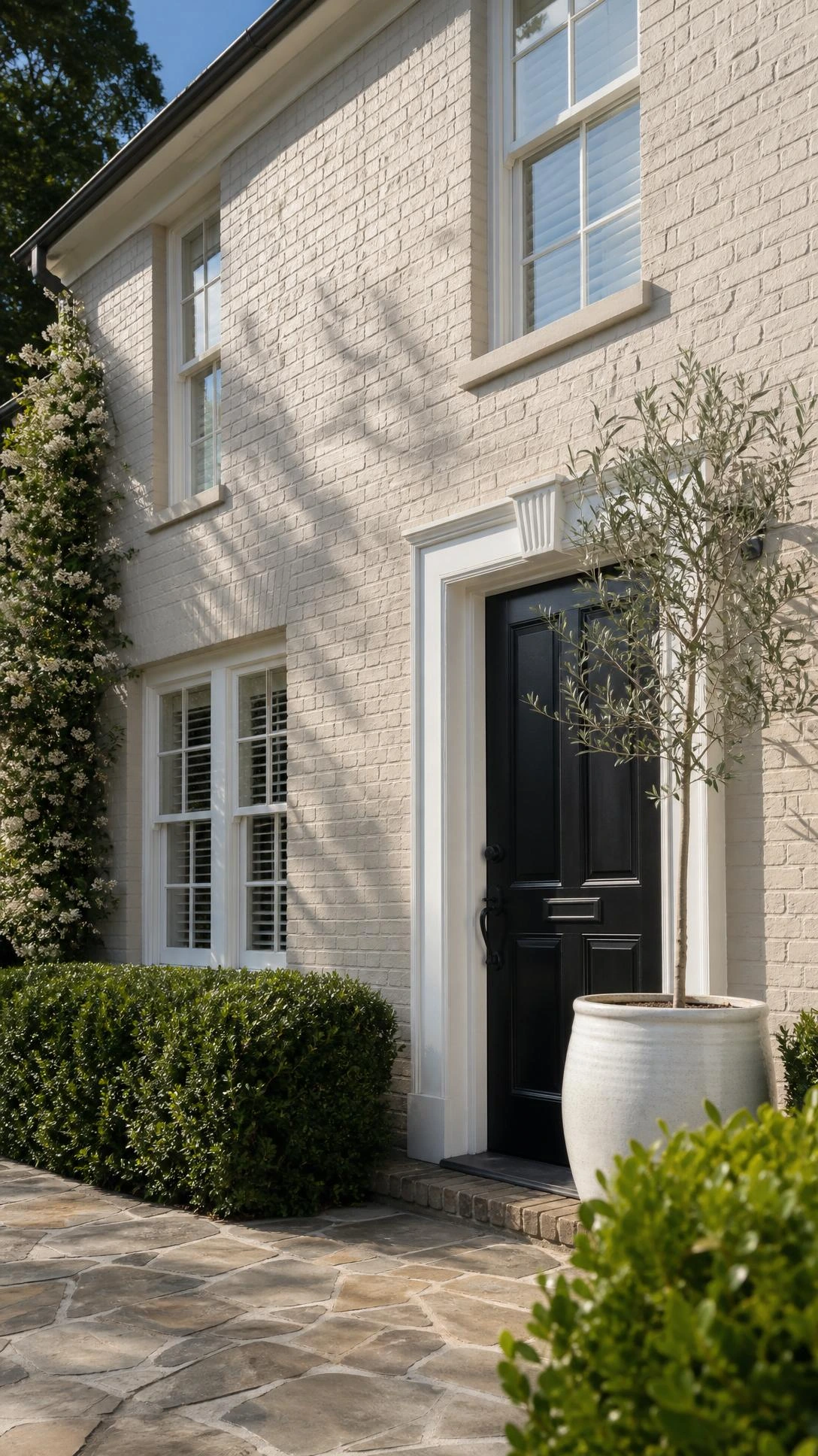 Traditional brick home exterior painted in soft warm greige, showing textured brushwork in natural sunlight — a classic curb appeal transformation technique