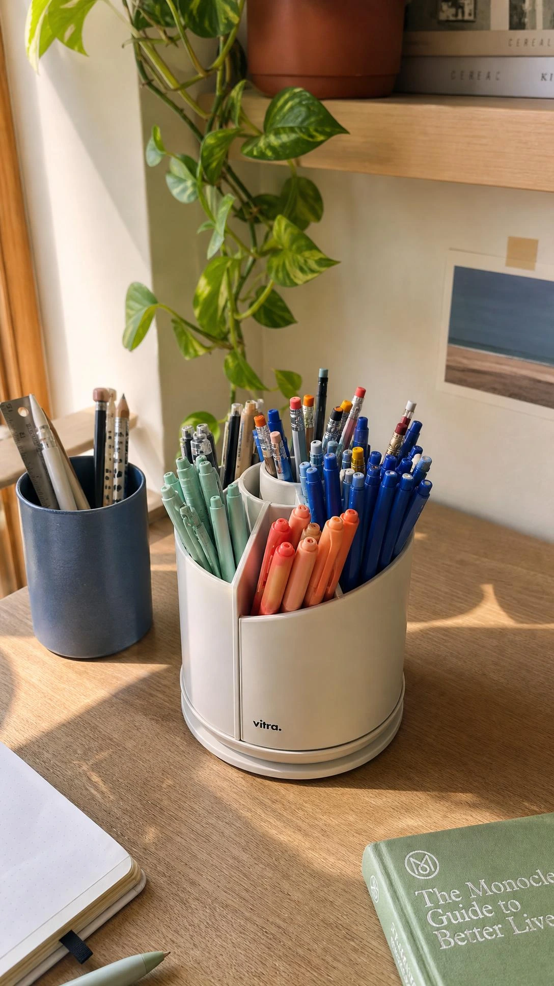 Modern rotating desk caddy with multiple compartments holding pens and supplies on a light oak home office desk