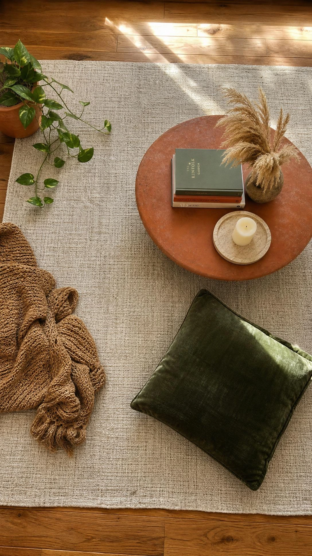 Overhead flat lay of a large neutral linen area rug in warm oatmeal and greige tones, anchoring a styled floor vignette with visible natural weave texture