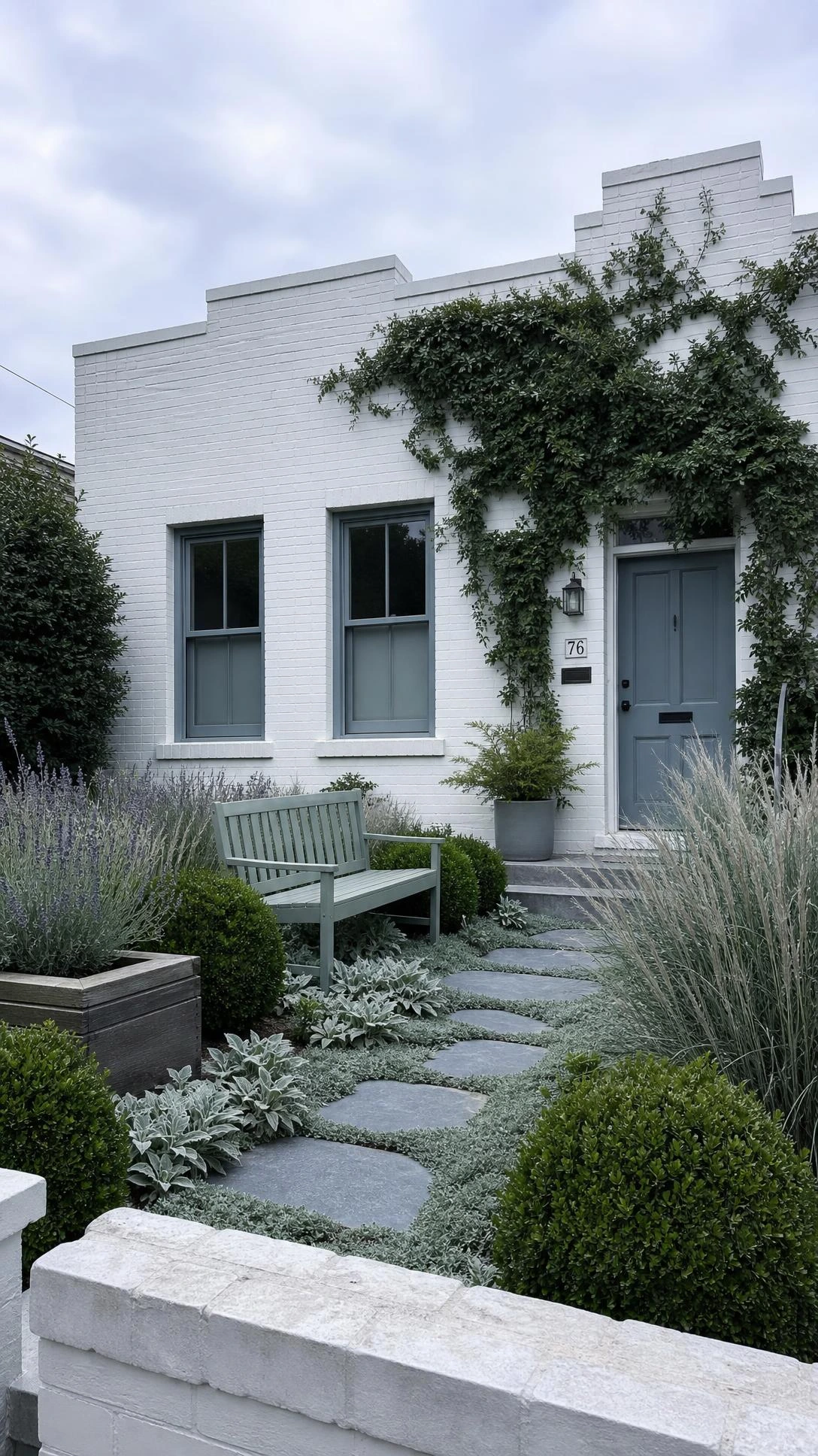 Small urban house exterior with deep forest green climbing plants and cool-toned garden border creating a restrained, sophisticated curb appeal