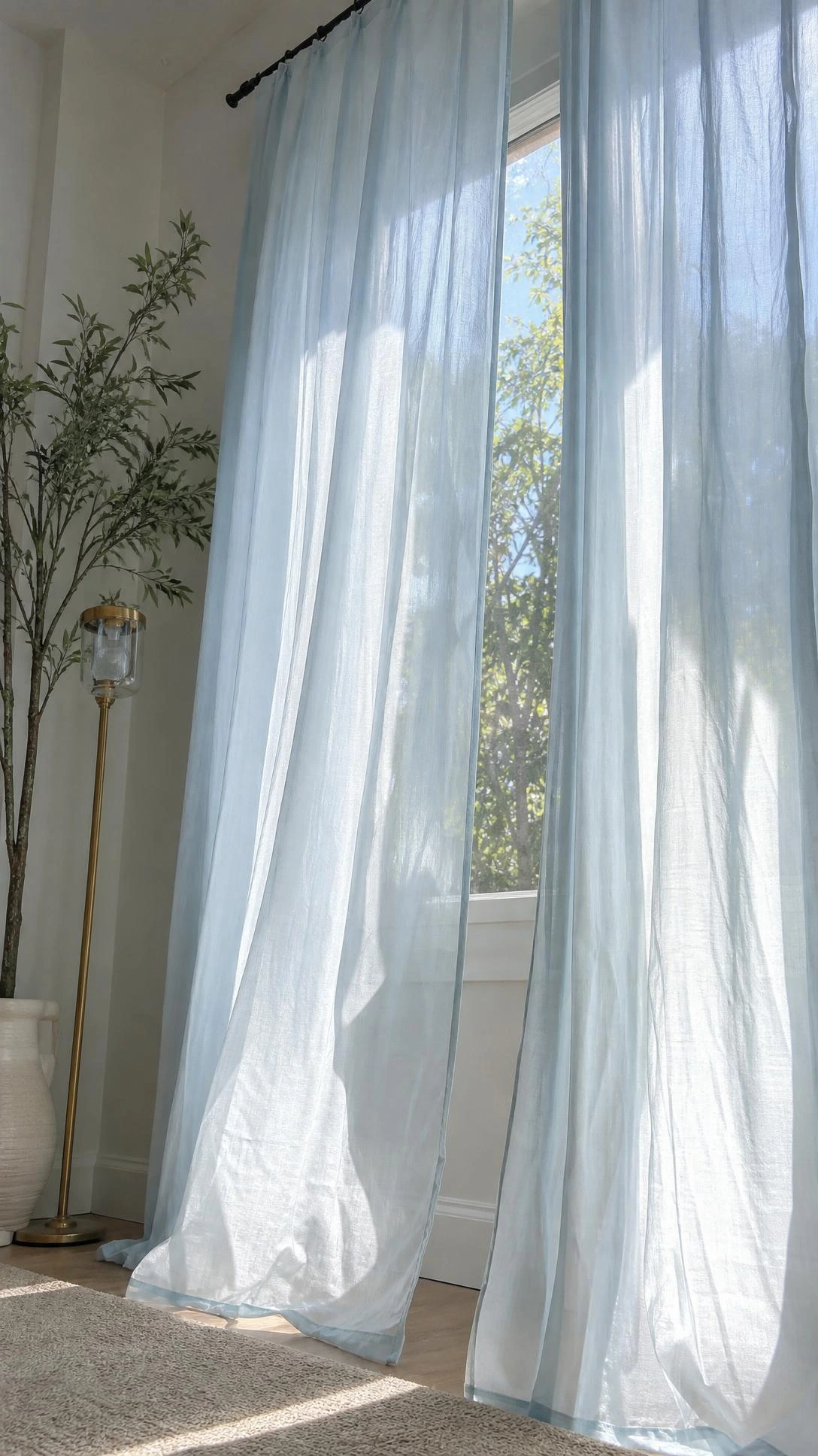 Breezy sheer curtains in pale blue and white soften a sunny window with plenty of daylight.
