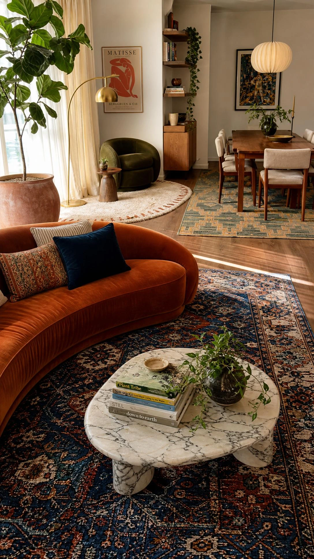Open-concept living and dining room with three distinct rugs defining separate zones, warmly lit by natural daylight through tall linen curtains