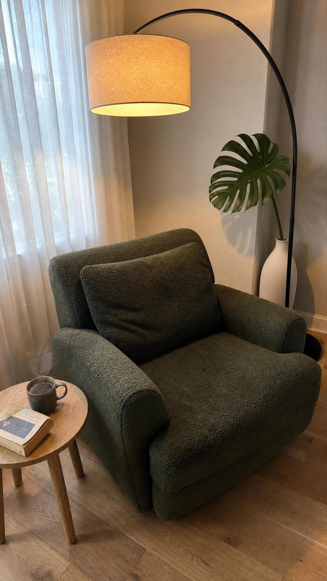 Matte black arc floor lamp sweeping over a plush reading chair in a cozy living room corner, transforming wasted space into a functional nook