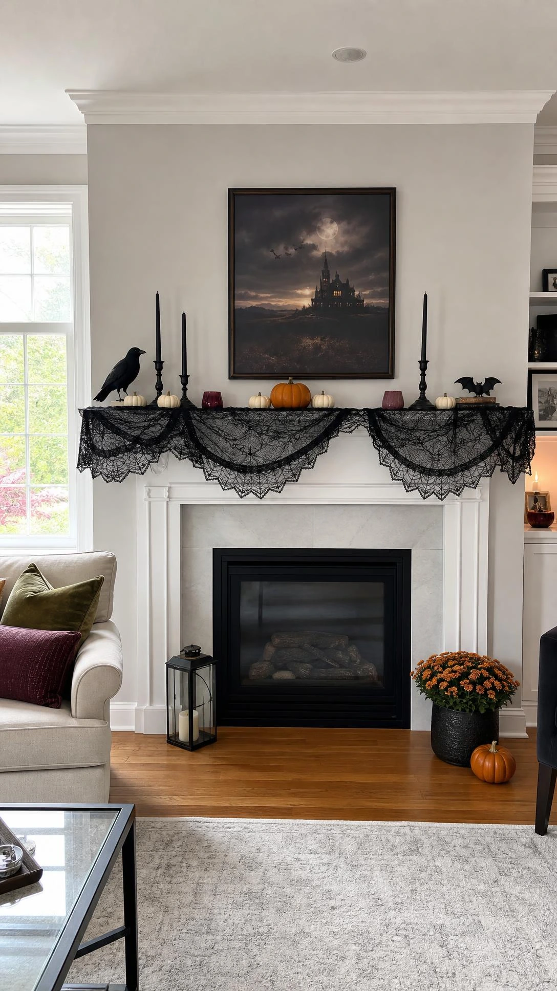 White fireplace mantel styled with black lace mantel decor, matte black candleholders, cream pumpkins, and plum votives for a refined Halloween look.