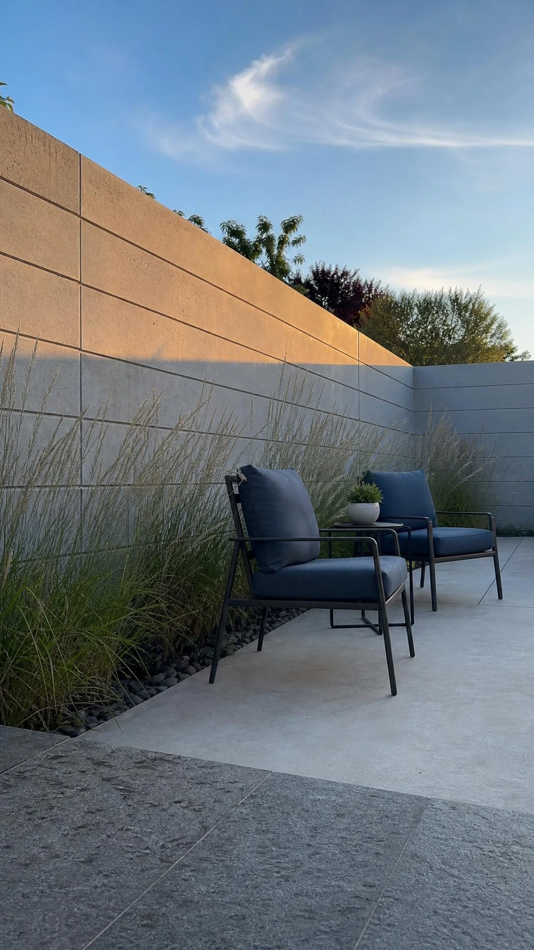 Built concrete privacy wall with horizontal grooves defining a modern backyard patio, showing how solid structures create complete seclusion