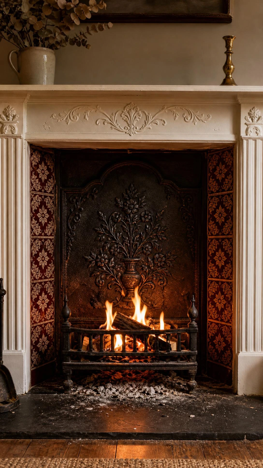 Ornate cast iron fireback with Victorian heraldic relief motif standing inside a firebox, reflecting amber firelight to maximize heat output