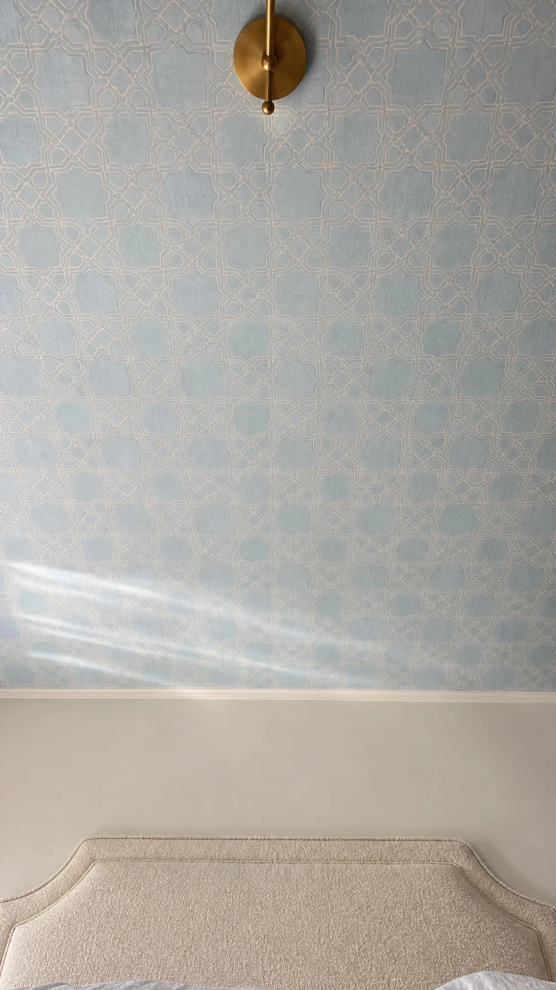 Bedroom ceiling covered in soft dusty blue and white geometric trellis wallpaper, viewed from directly below — a subtle, architectural pattern that transforms an overlooked surface into a quiet focal point