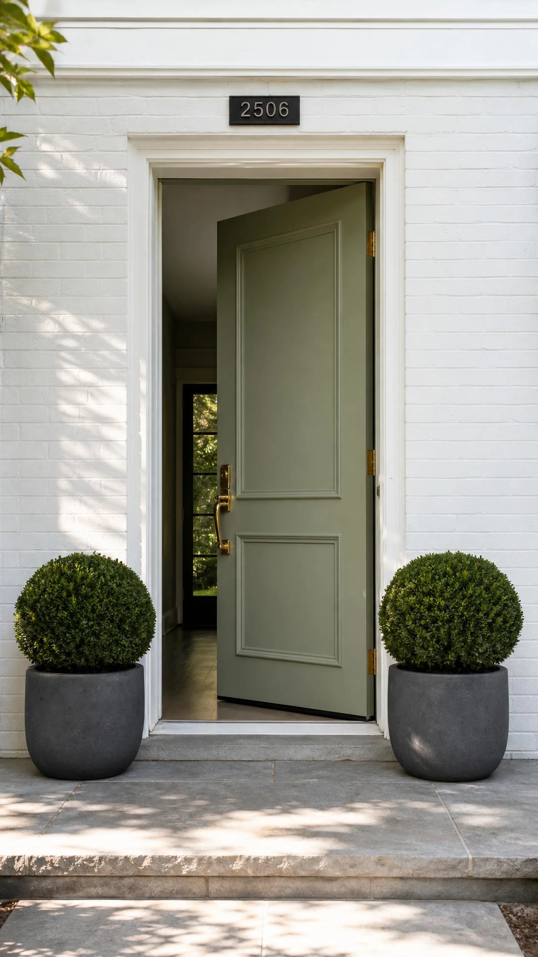 Matched pair of matte charcoal concrete planters flanking a white front door on a light gray porch — minimal front yard landscaping done right