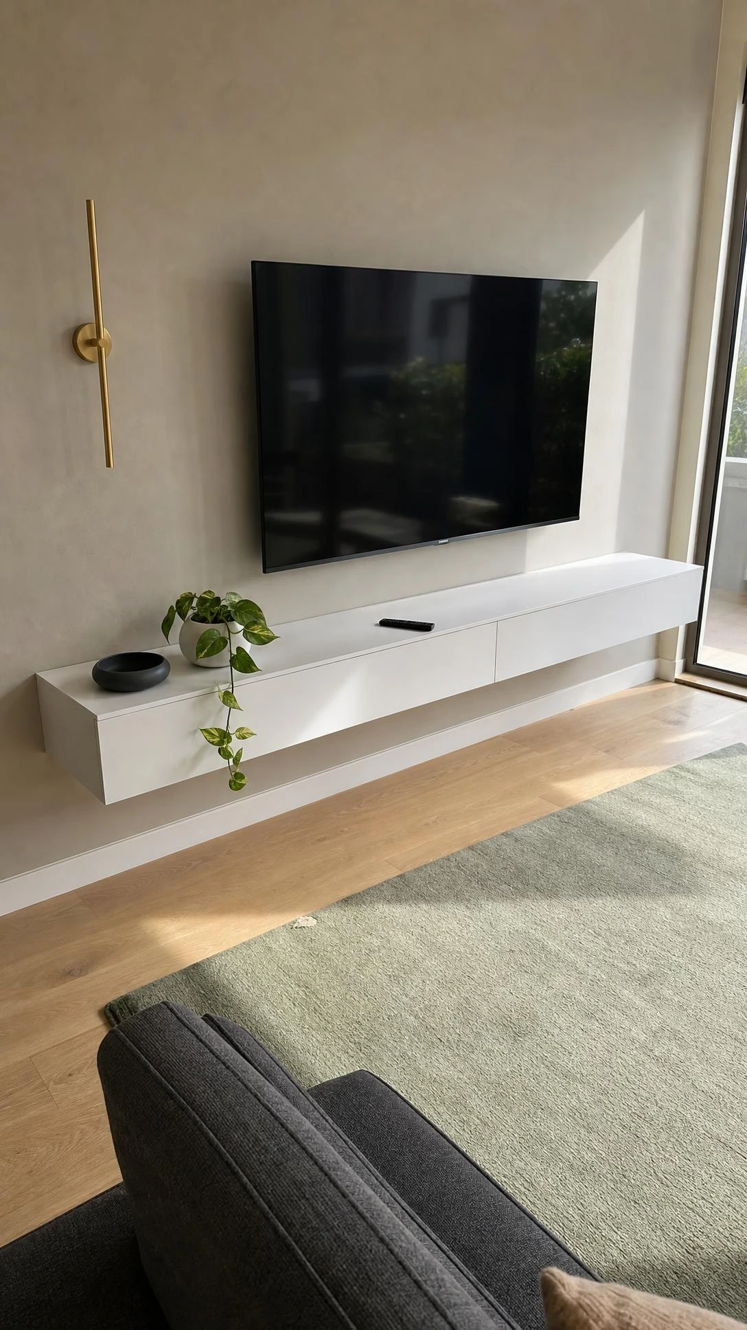 Floating matte white TV unit with integrated cable channel keeping wires hidden in a bright modern living room