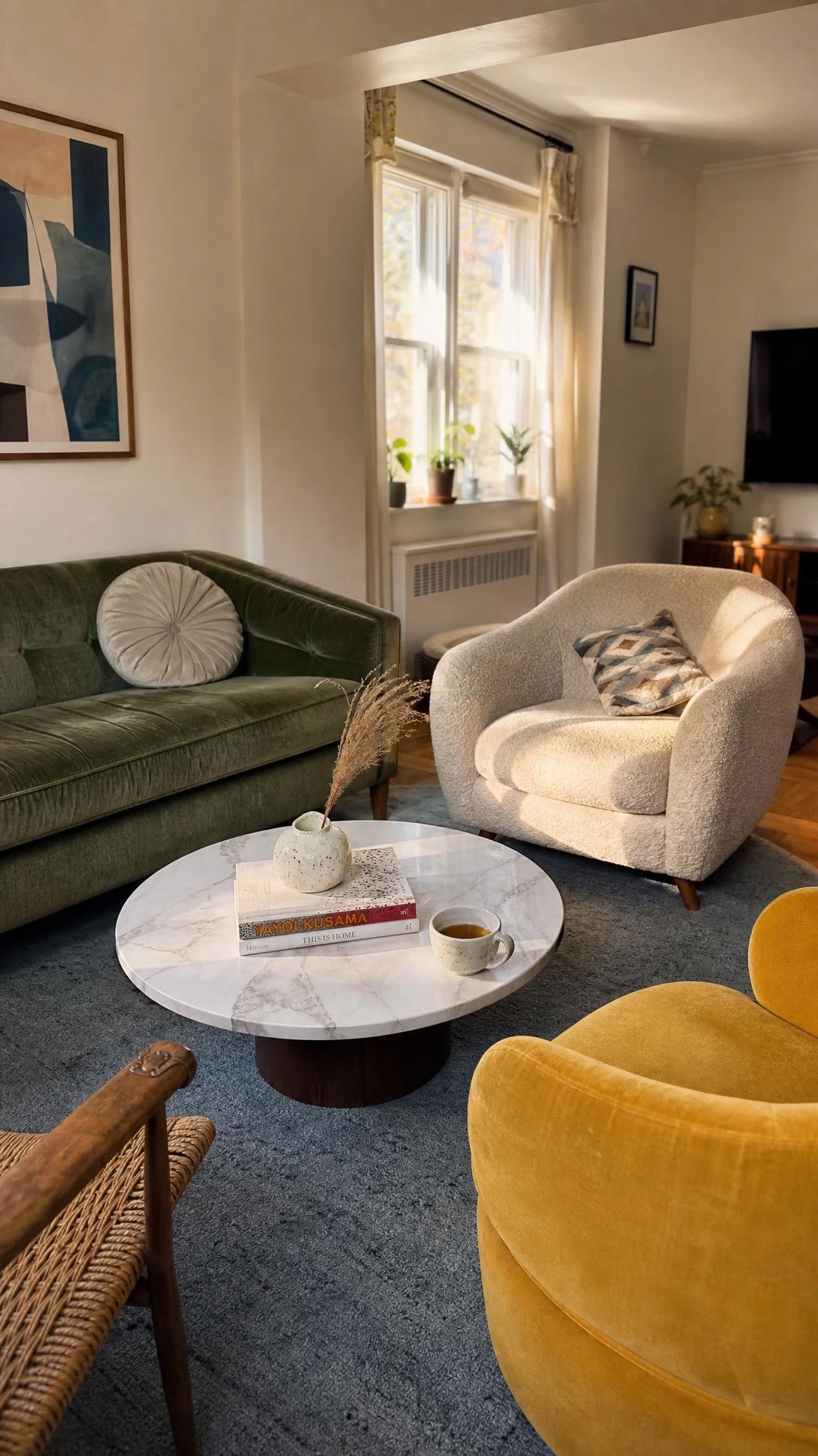 Sage green velvet sofa and mismatched armchairs arranged in a circular conversation grouping, deliberately turning away from the wall-mounted TV