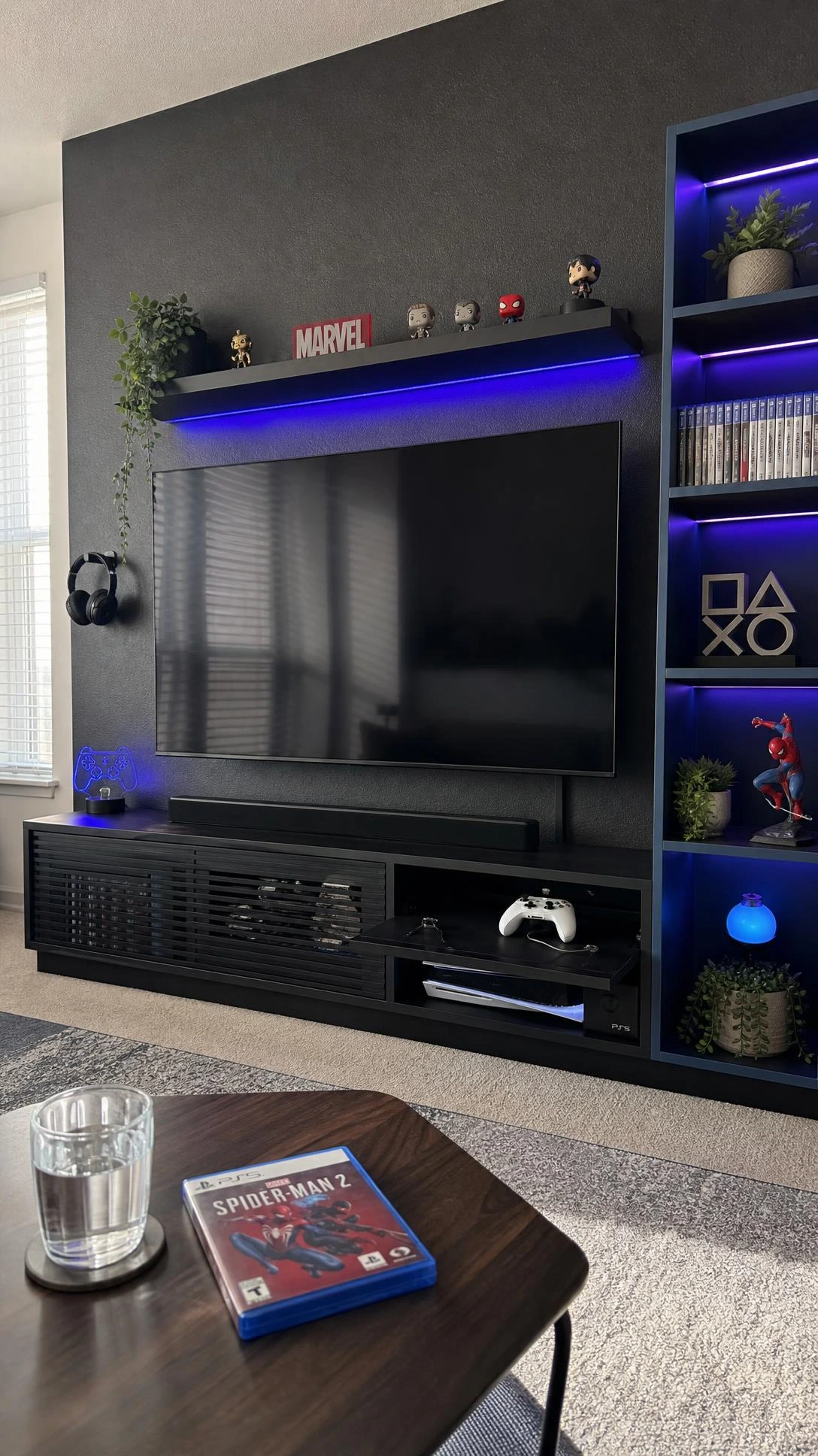 Matte black gaming TV unit with dedicated console cable management built into a floor-to-ceiling navy shelving tower against a charcoal accent wall
