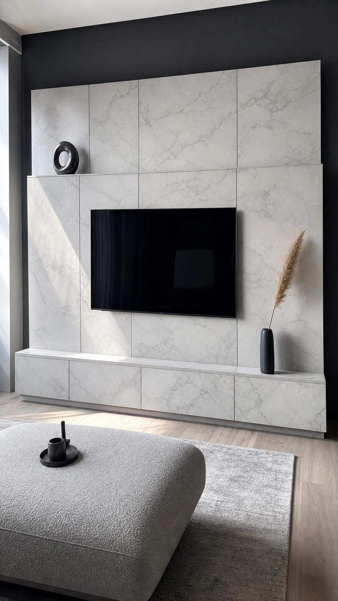 Floor-to-ceiling marble-look TV unit with pale grey veining and flush-mounted television, showing how a stone-finish media wall hides cables completely