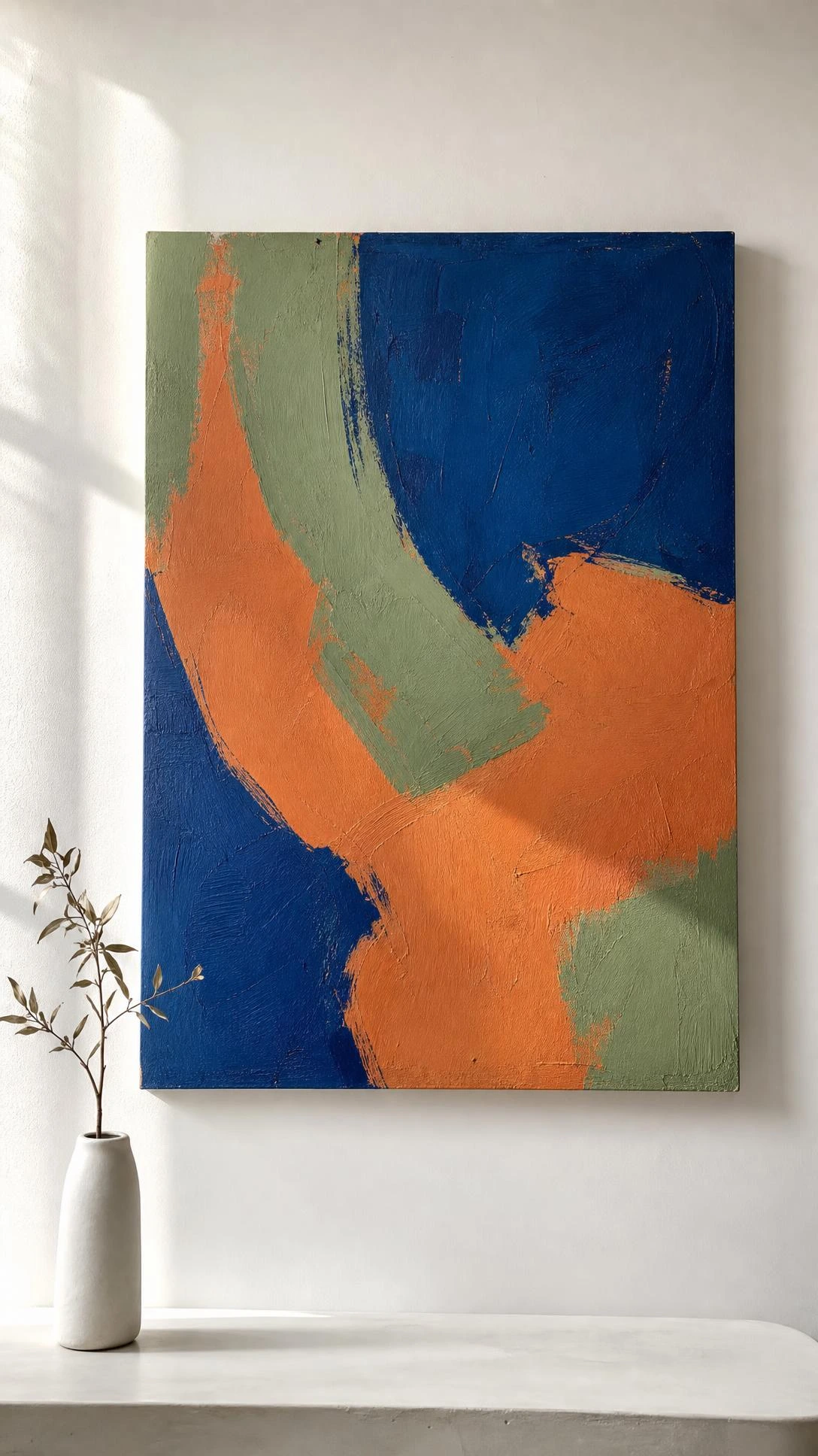 Large abstract painting in cobalt blue, terracotta, and sage green hung alone on a white wall, showing how a single bold art piece anchors a minimalist room