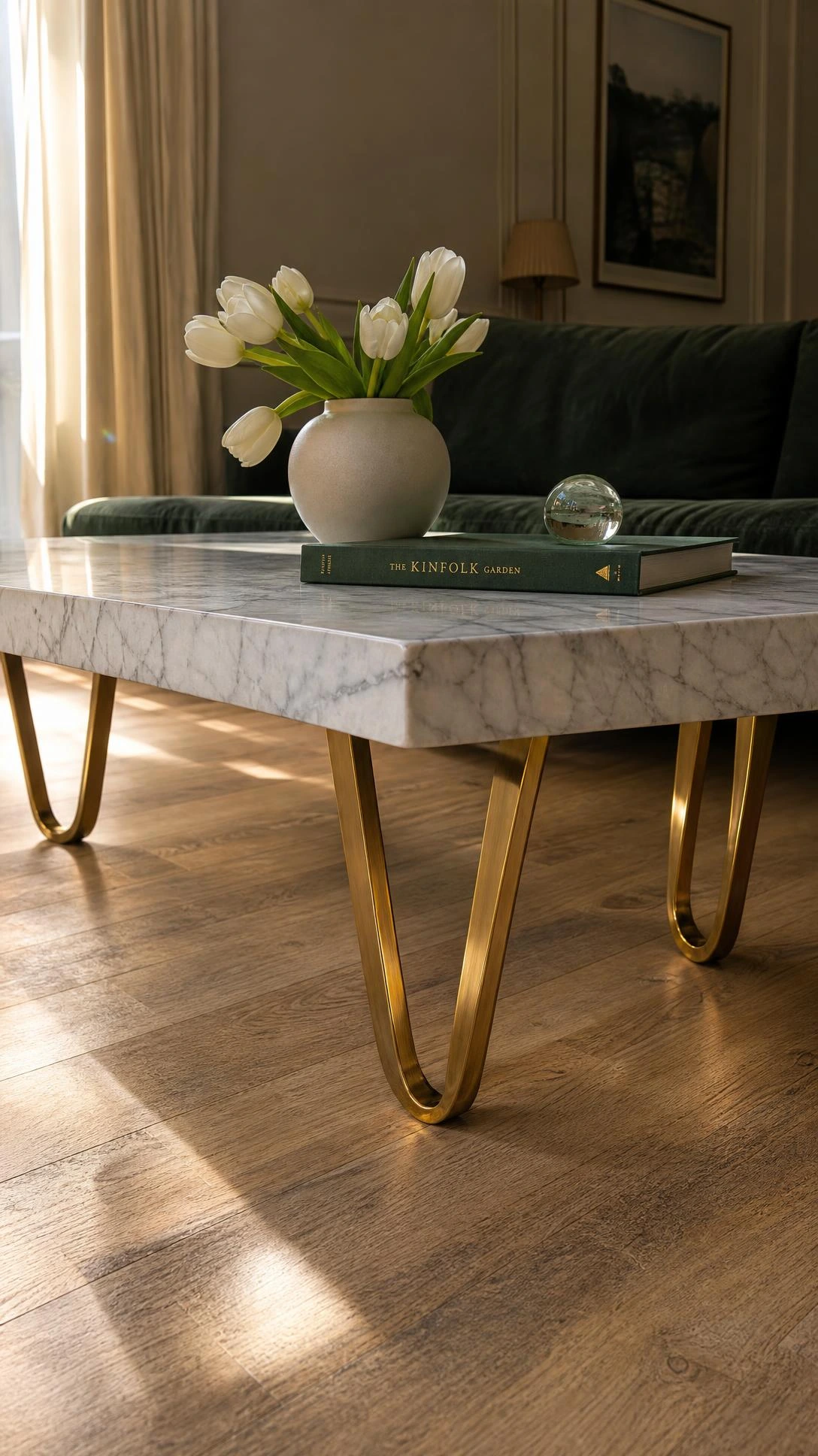Polished white marble coffee table with grey veining on sculptural brushed brass legs, photographed from floor level to emphasize its bold statement presence in a drawing room