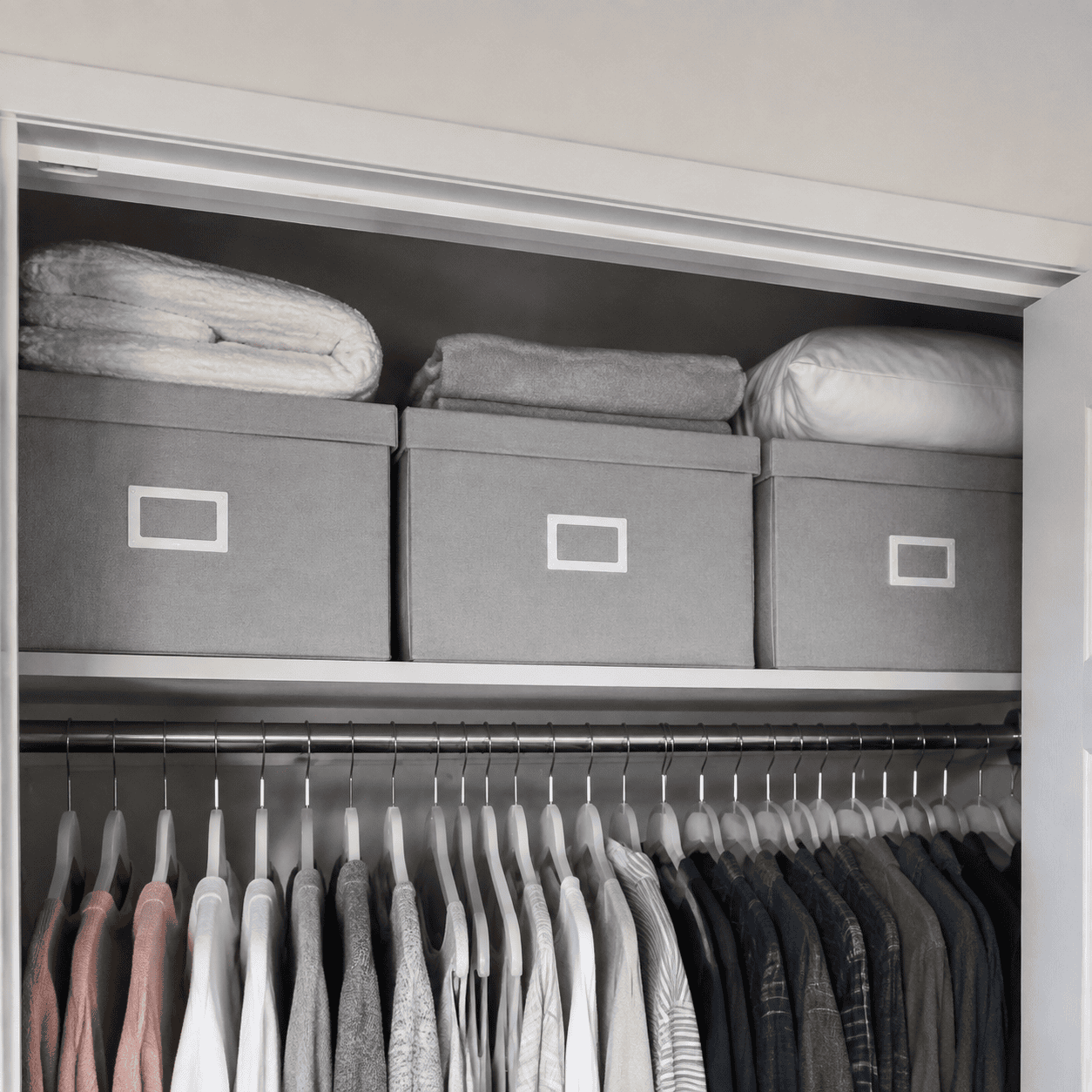 Matching storage boxes arranged on a bedroom closet shelf