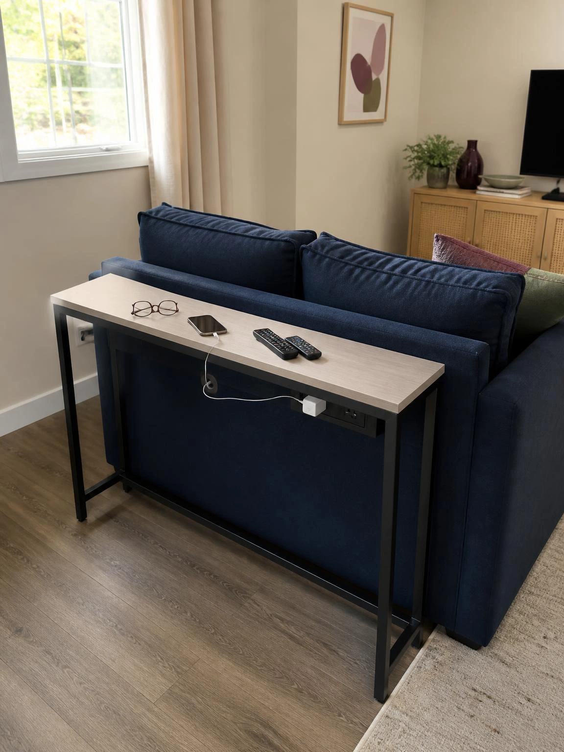 Narrow sofa table with built-in outlets behind a navy sofa, keeping charging organized without blocking the small living room walkway
